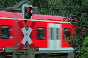 Ein Andreaskreuz mit rotem Blinklicht warnt Sie vor einem herannahenden Zug.